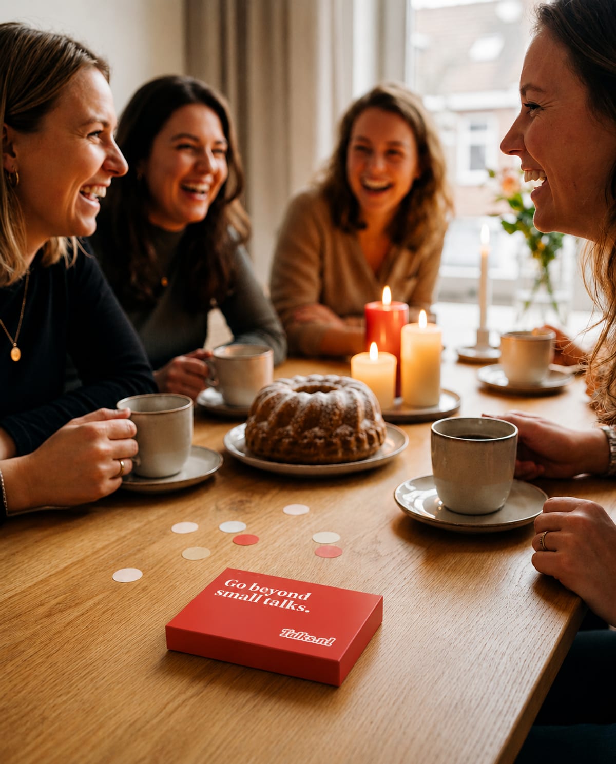 Vriendinnen aan een gedekte tafel thuis, met op de voorgrond het vlamrode Talks.nl cadeaudoosje waar de cadeaupas uit schuift